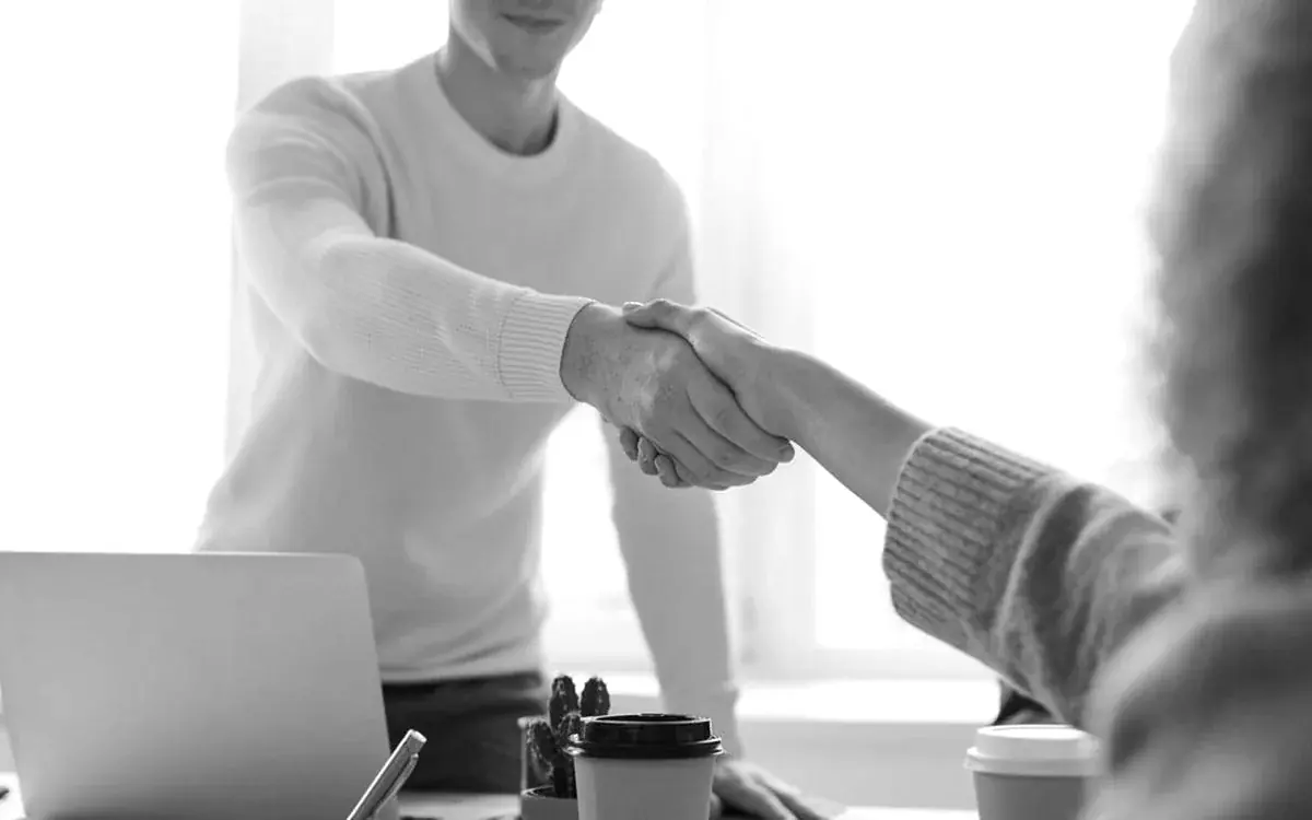 Business partners shaking hands across a desk